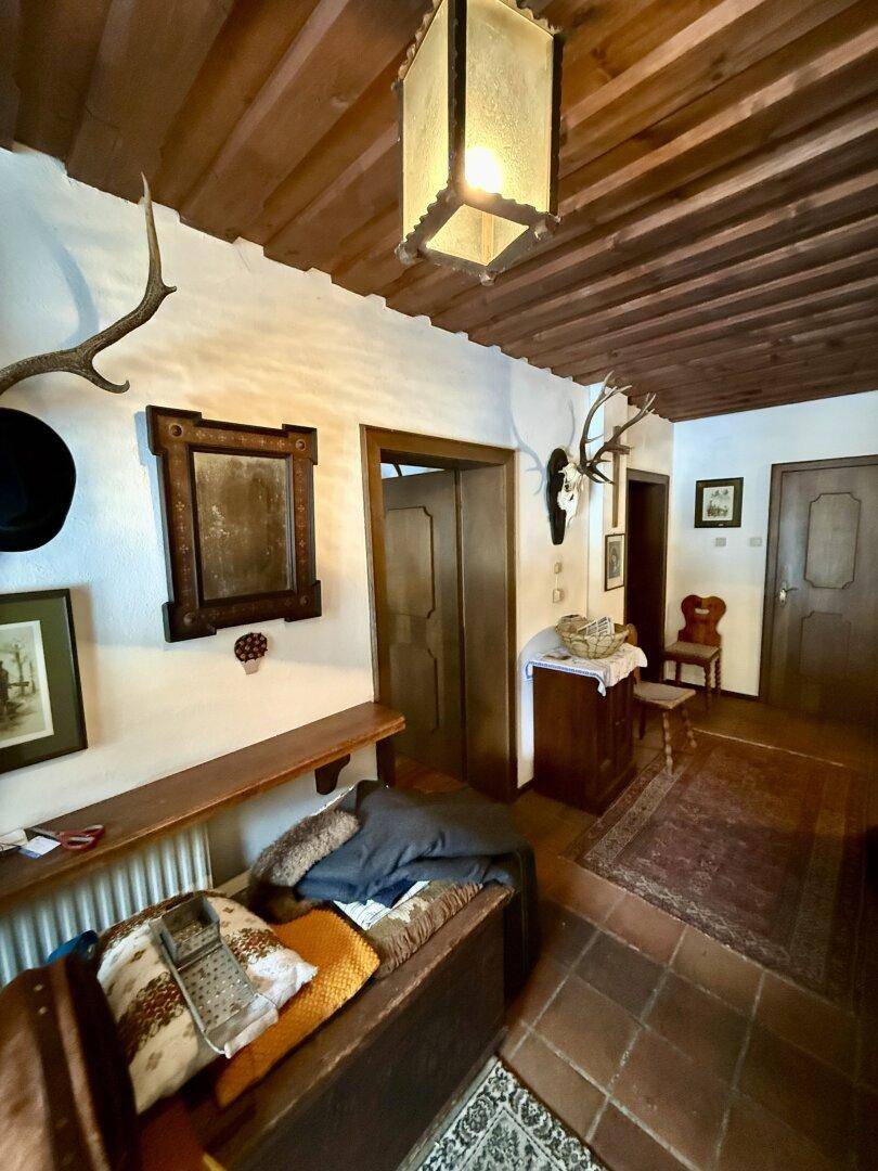 Rustikaler Eingangsbereich mit Holzbalkendecke, Fliesenboden und traditioneller Dekoration.