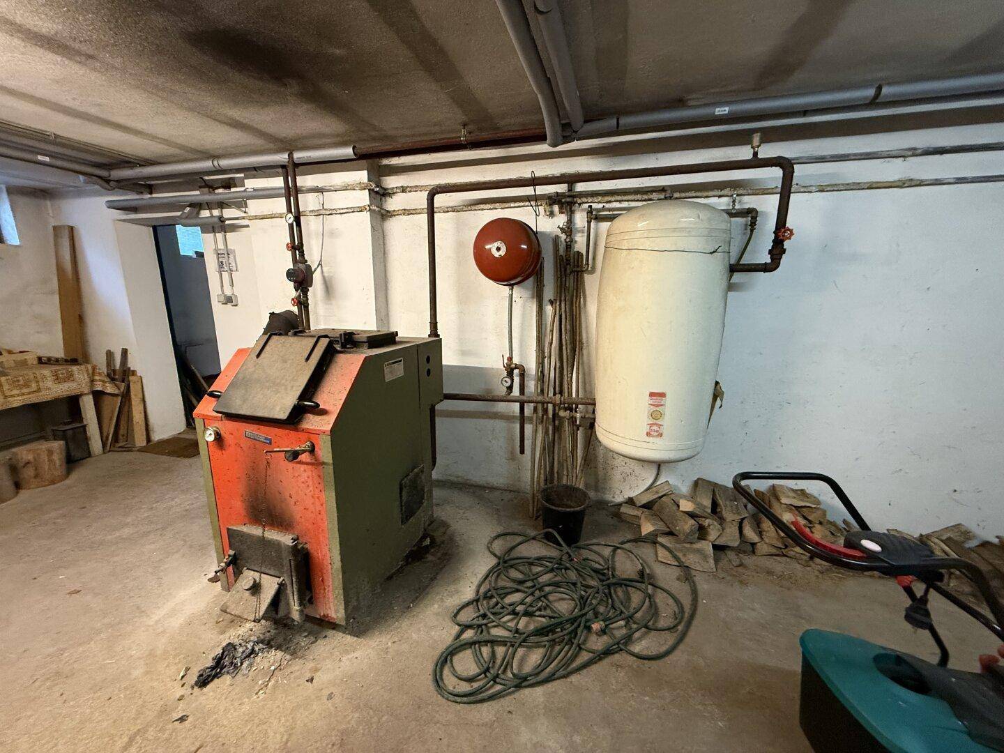 Heizungsraum im Keller mit Holzofen und Warmwasserspeicher für die Warmwasserversorgung.
