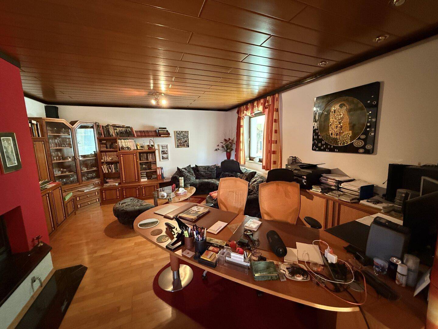 Großzügiger Wohnbereich mit Holzboden, Holzdecke und integriertem Arbeitsplatz.