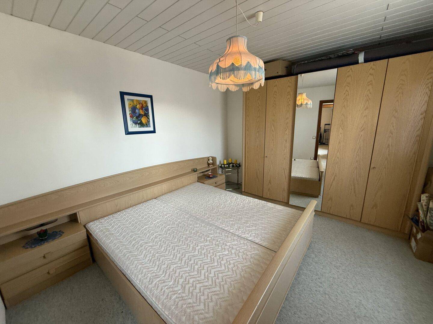 Schlafzimmer mit Doppelbett, Einbauschränken und hellem Holzmobiliar.