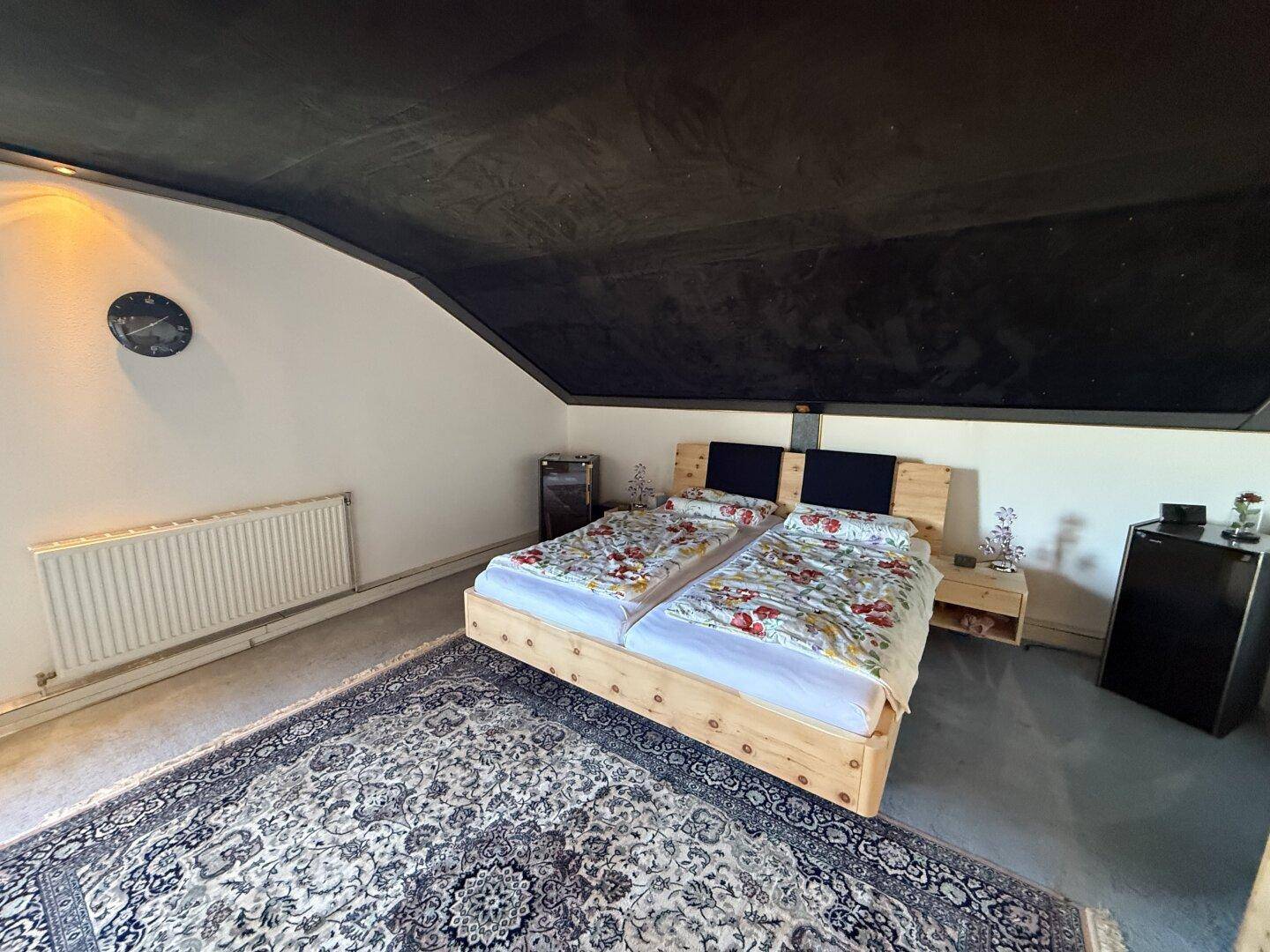 Dachgeschoss-Schlafzimmer mit zwei Einzelbetten, Teppichboden und schräger Decke.