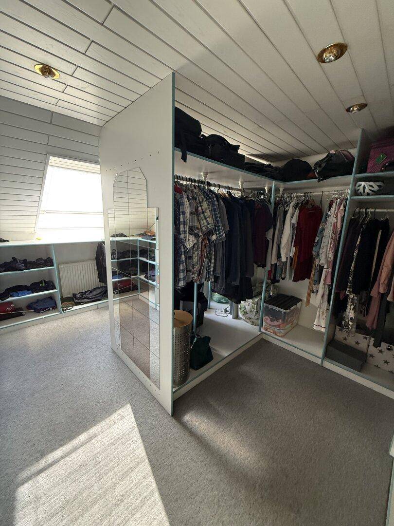 Begehbarer Kleiderschrank im Dachgeschoss mit viel Stauraum und Dachfenster.