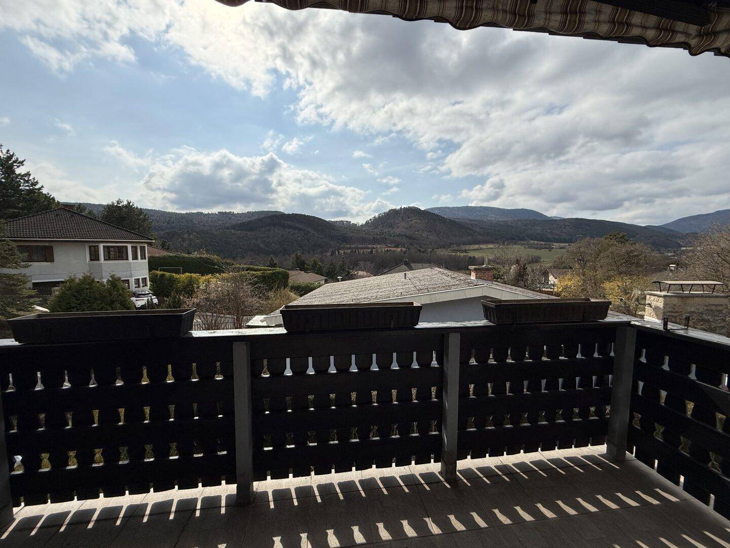 Weitblick vom Balkon über die Landschaft mit Bergen und bewölktem Himmel, sehr idyllisch.