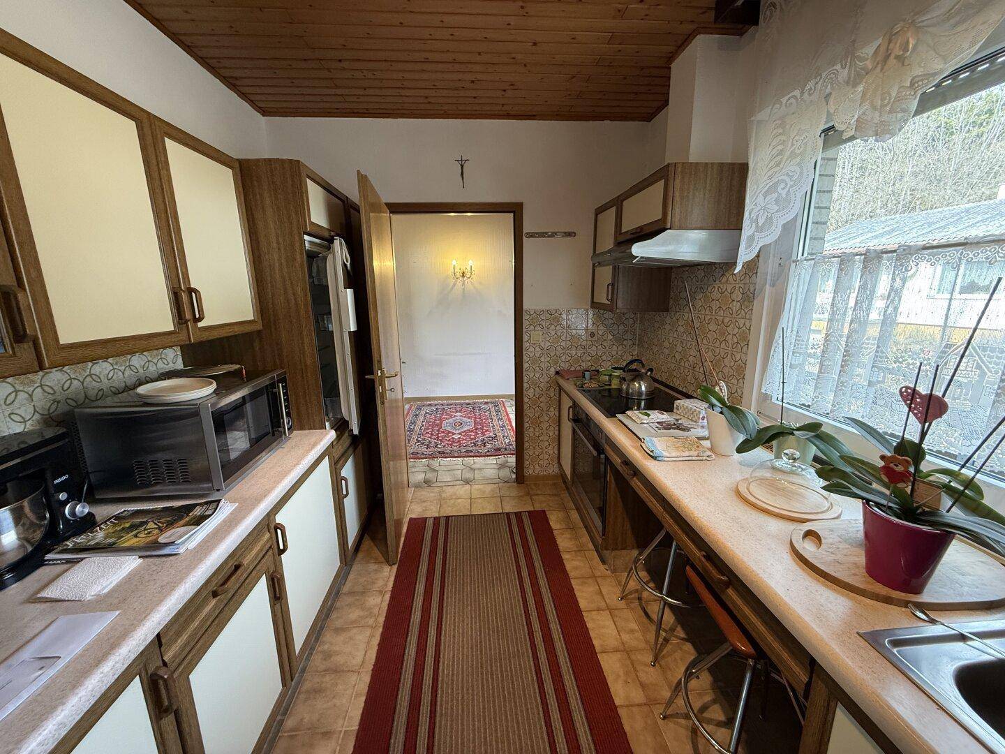 Küche mit Arbeitsplatte, Spüle und Fenster, das viel Tageslicht hereinlässt, sehr hell.