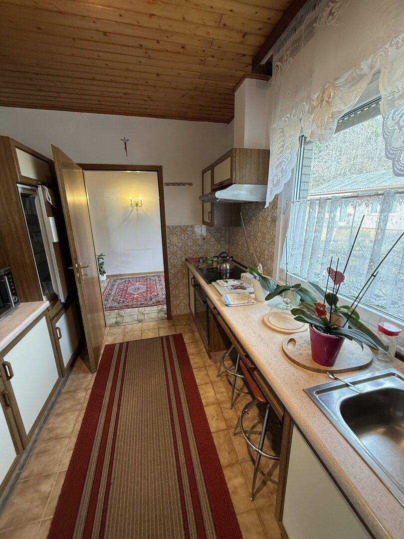 Traditionelle Küche mit Holzdecke, Fliesenboden und Blick ins Grüne, sehr funktional.
