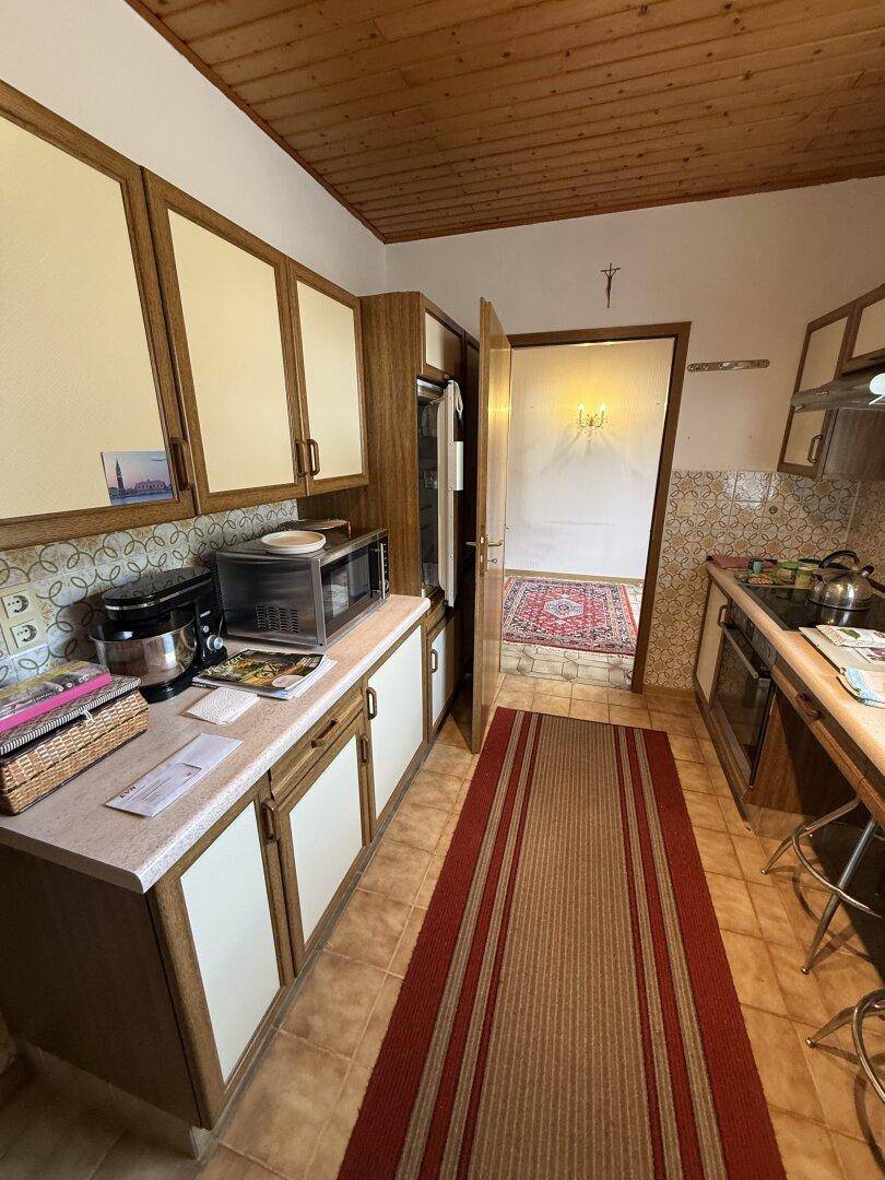 Funktionale Küche mit Einbauschränken, Mikrowelle und traditionellem Design, gut ausgestattet.