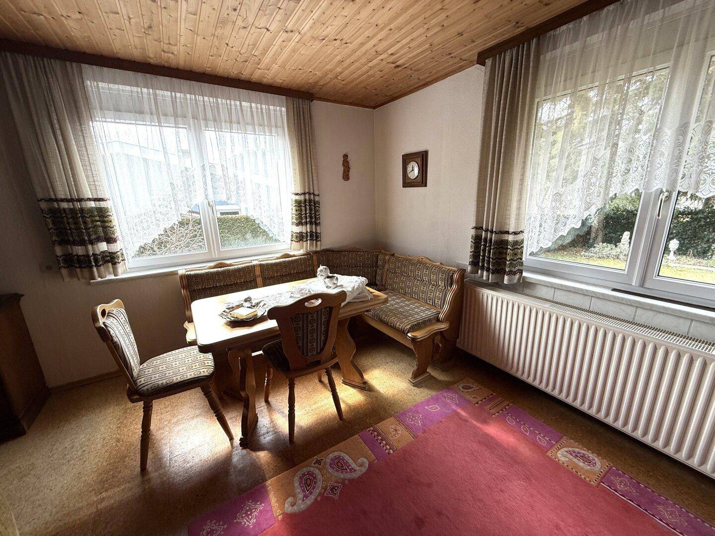 Gemütlicher Essbereich im Wohnzimmer mit Eckbank und Blick nach draußen, sehr traditionell.