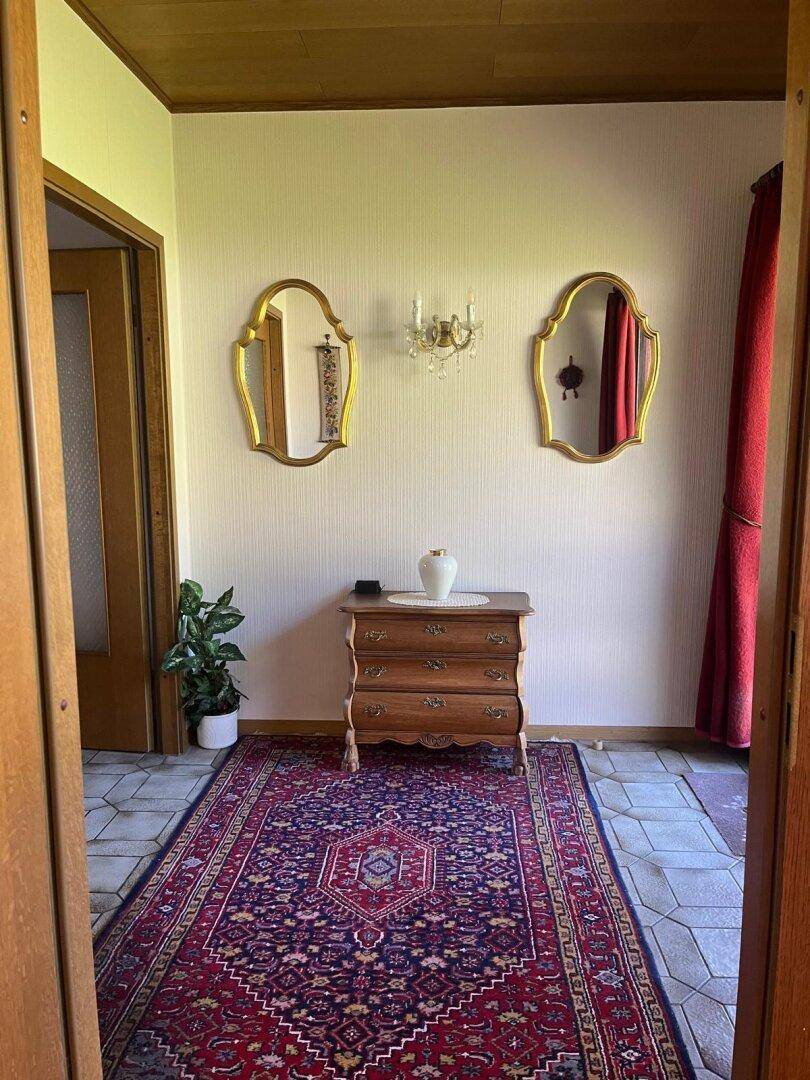 Gemütlicher Flur mit Holzdecke, Fliesenboden und dekorativen Spiegeln, einladend gestaltet.