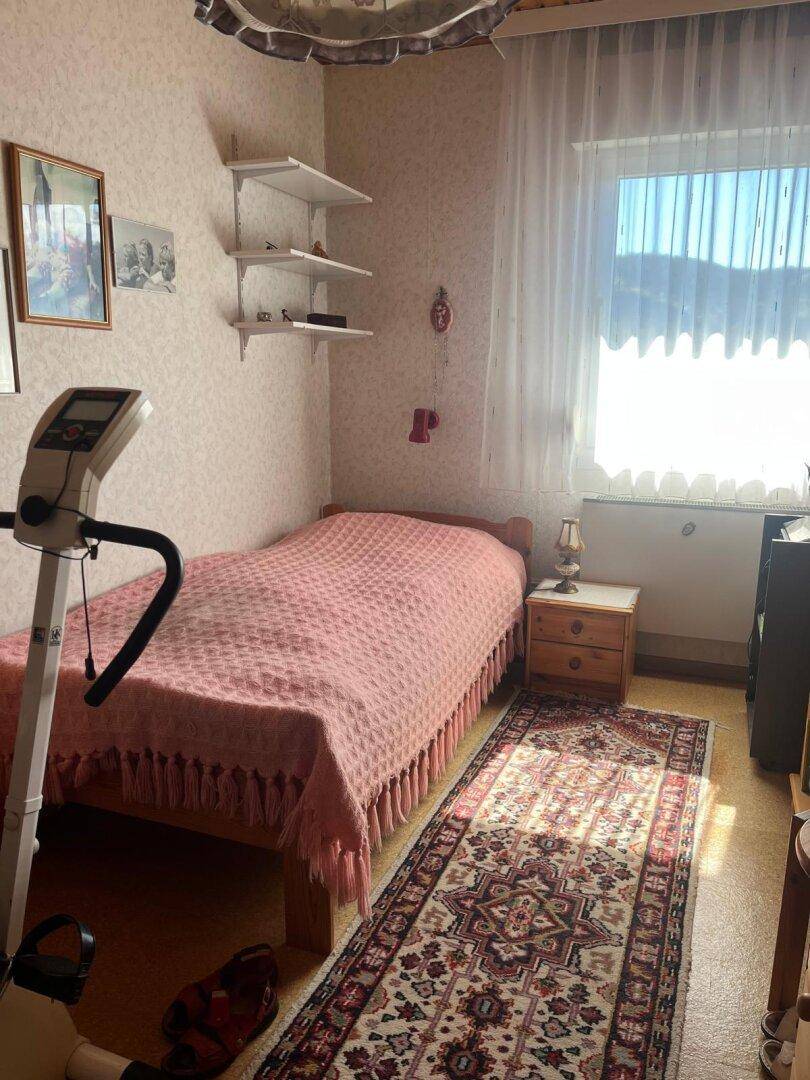 Helles Schlafzimmer mit Einzelbett, Schreibtisch und Fenster mit Blick nach draußen, sehr gemütlich.