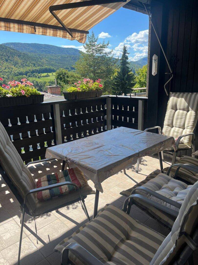 Gemütlicher Balkon mit Markise, Sitzmöbeln und herrlichem Bergblick, sehr einladend.