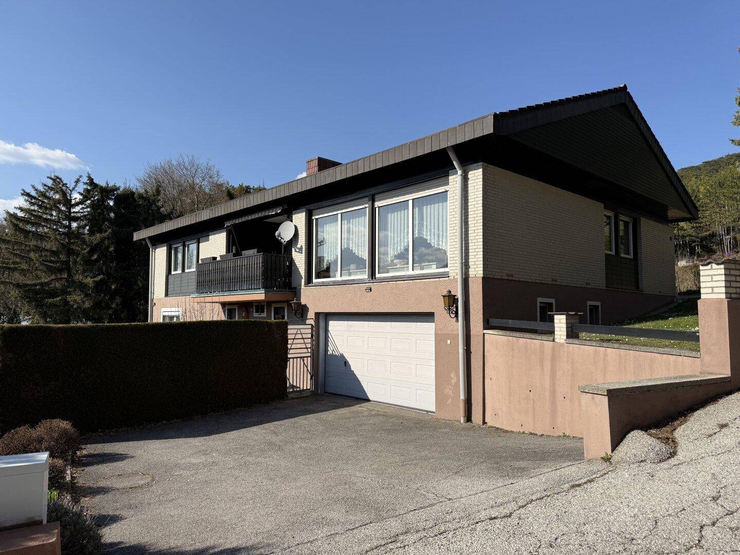 Das Wohnhaus mit Garage und gepflegter Einfahrt unter blauem Himmel.