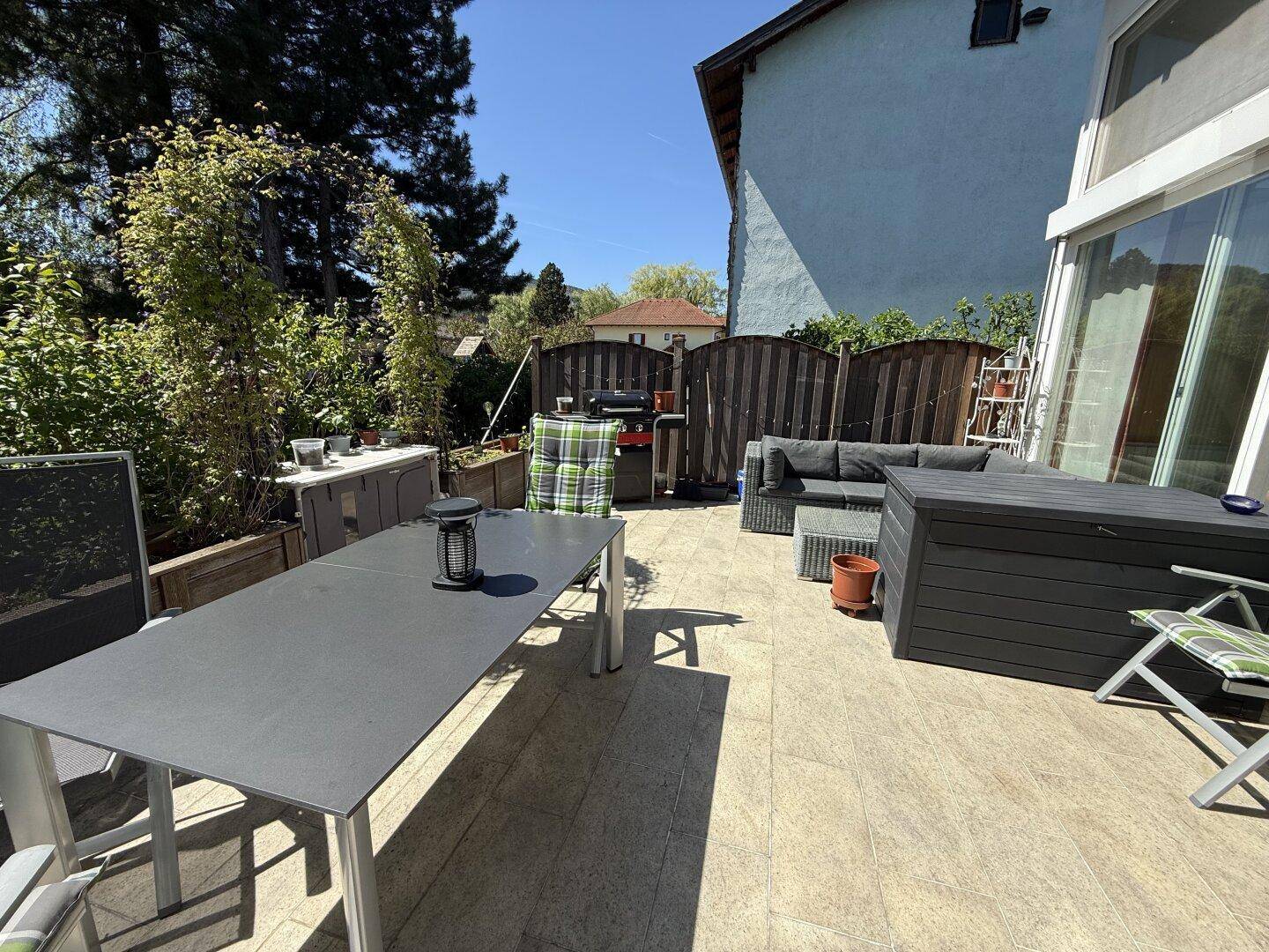 Geräumige Terrasse mit modernen Gartenmöbeln, Grill und Blick auf den Gartenbereich.
