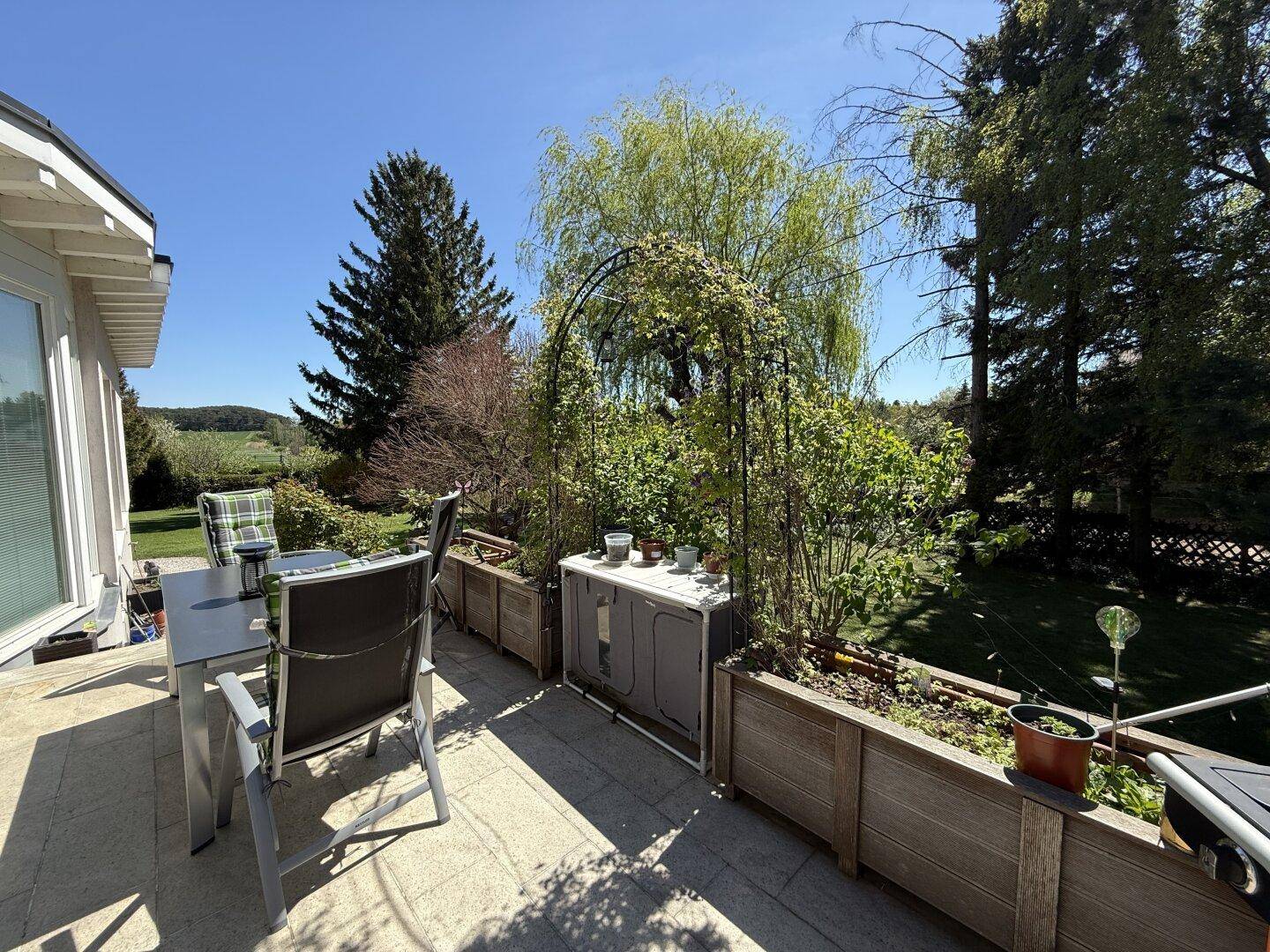 Terrasse mit Pflanzbeeten und Sitzgelegenheiten, bietet einen schönen Ausblick in die grüne Landschaft.