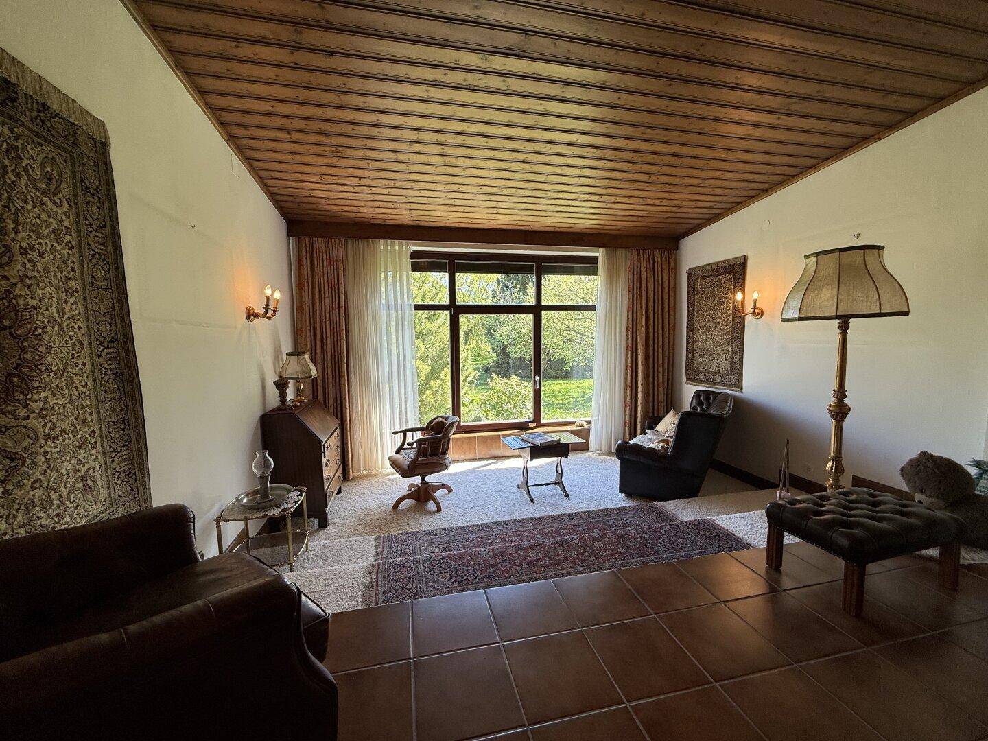Geräumiges Wohnzimmer mit großem Fenster, das viel Tageslicht und Gartenblick bietet.