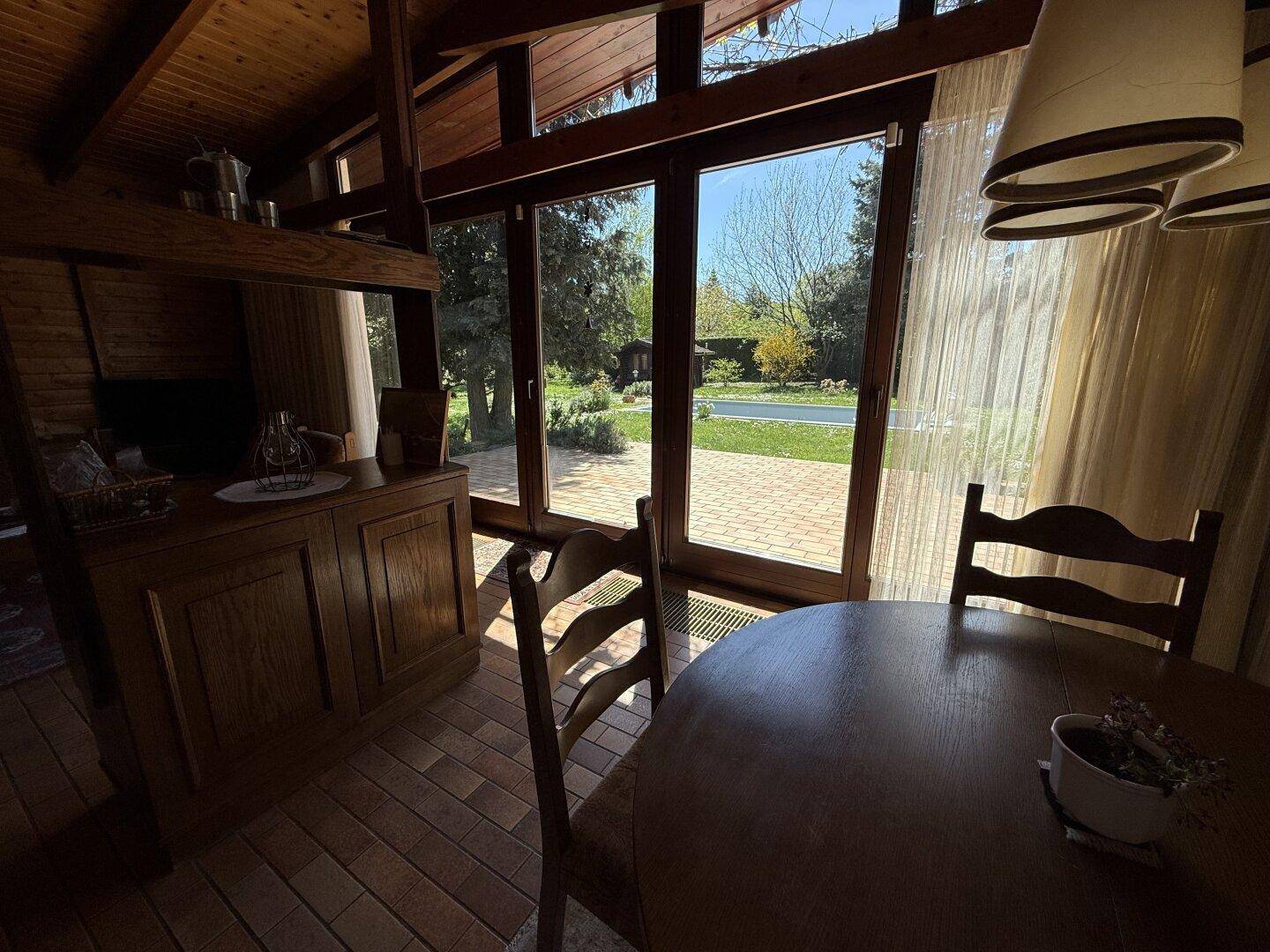 Essbereich mit Holztisch und Stühlen, bietet einen schönen Blick auf den Garten und Pool.