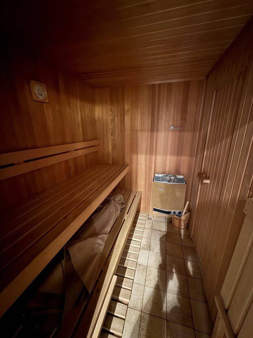 Gemütliche Holzsauna mit Bänken und traditionellem Saunaofen für Entspannung.