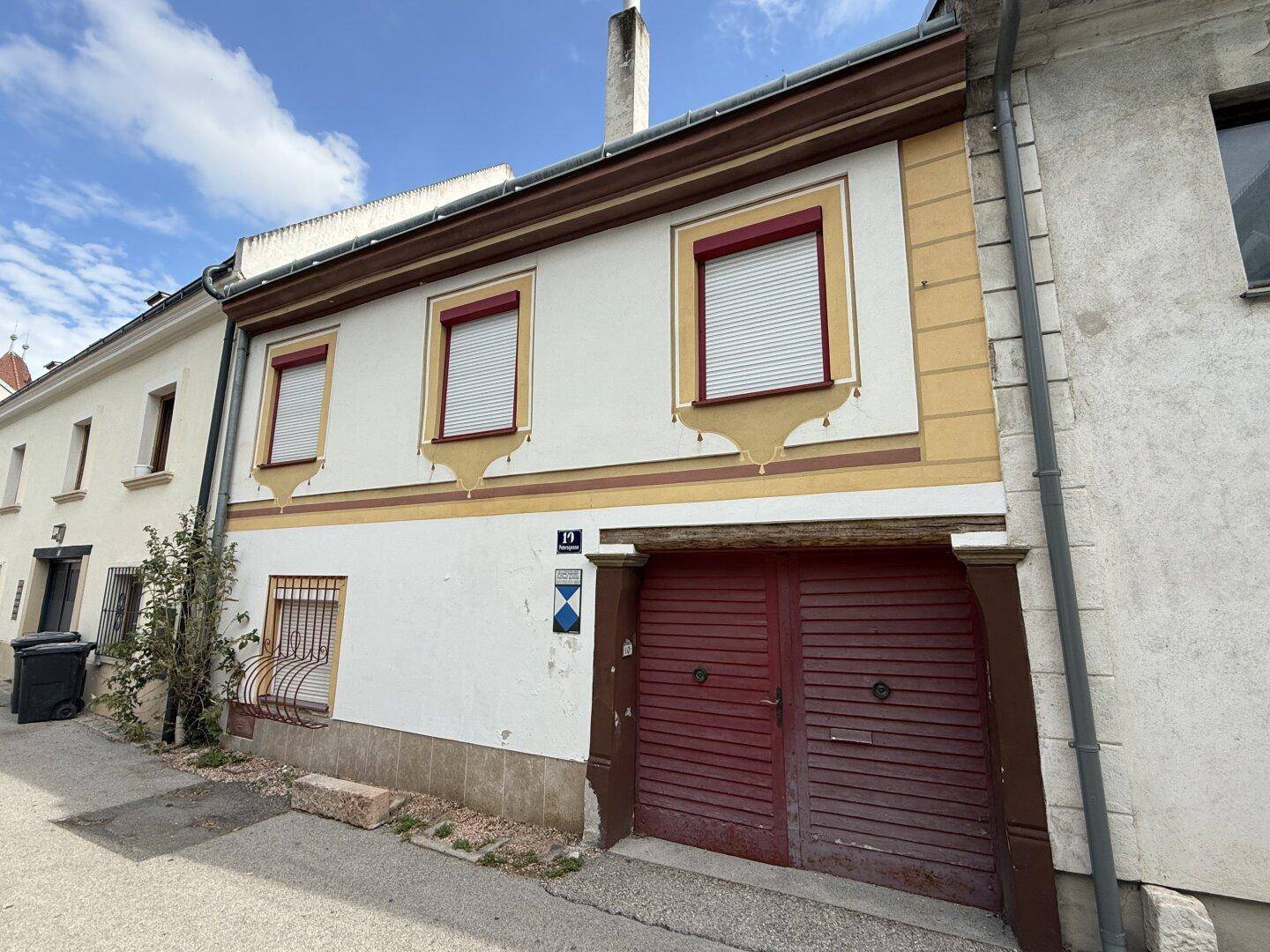 Traditionelle Hausfassade mit dekorativen Elementen, Fensterläden und einem großen Holztor.