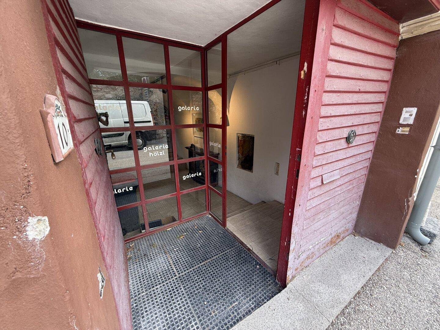 Eingangsbereich mit Glasfront und Treppe, die in die unteren Räume führt.