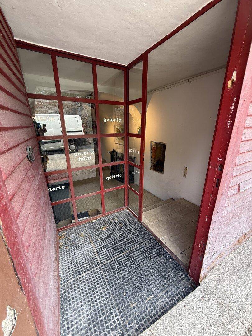 Eingangsbereich mit roter Glasfront und Treppe, die in die unteren Räume führt.