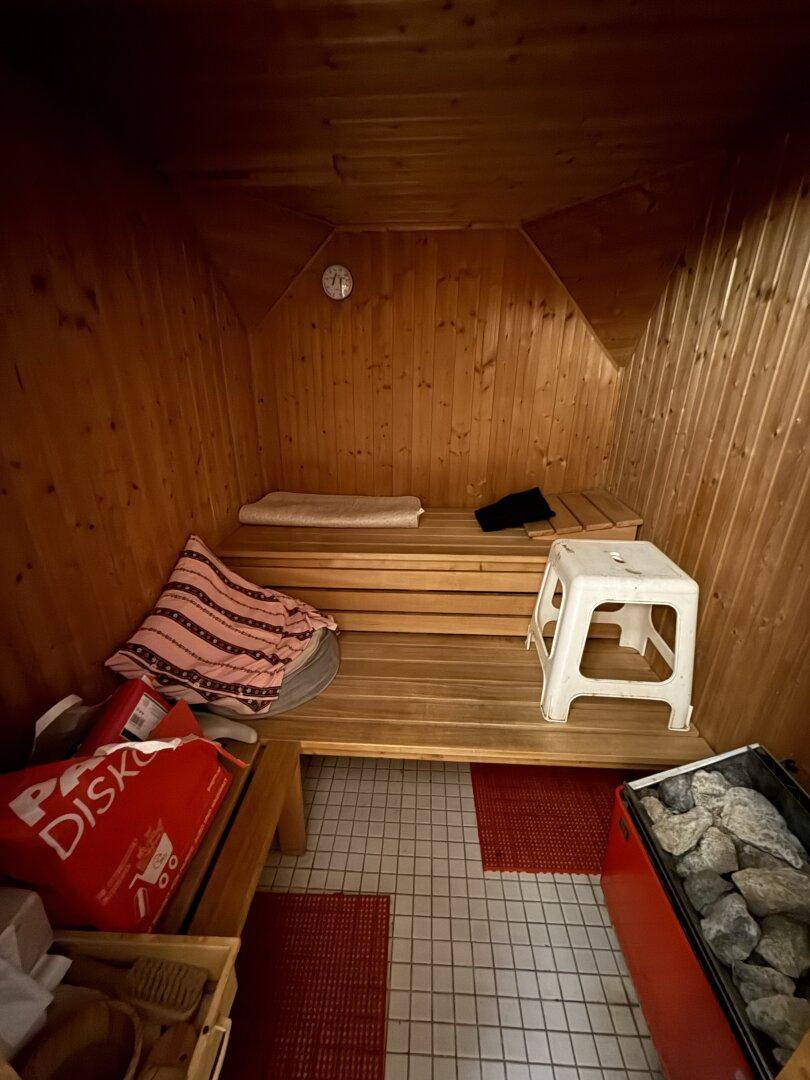 Holzvertäfelte Sauna mit Bänken und einem Saunaofen für Entspannung.