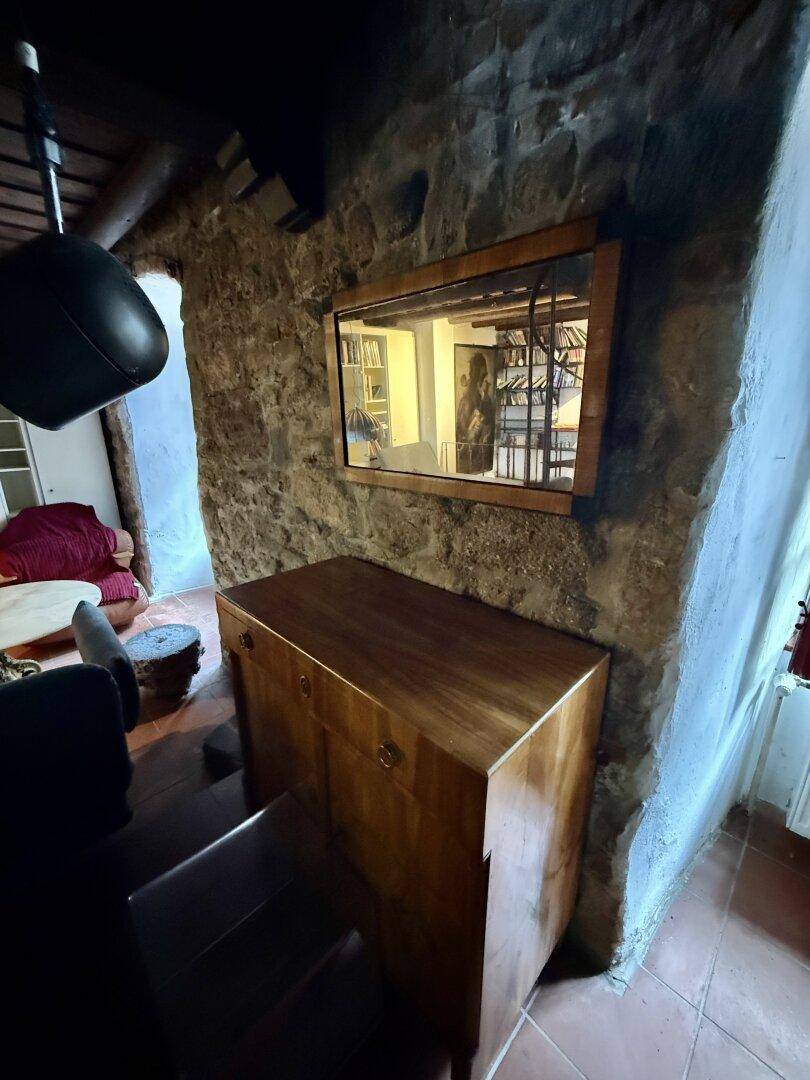 Flur mit Steinwand, Holzschrank und Terrakottafliesen, der zu weiteren Räumen führt.