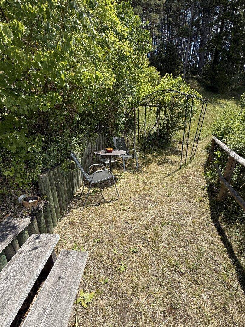 Kleiner, gemütlicher Gartenbereich mit Sitzgelegenheit und üppiger Bepflanzung am Hang.