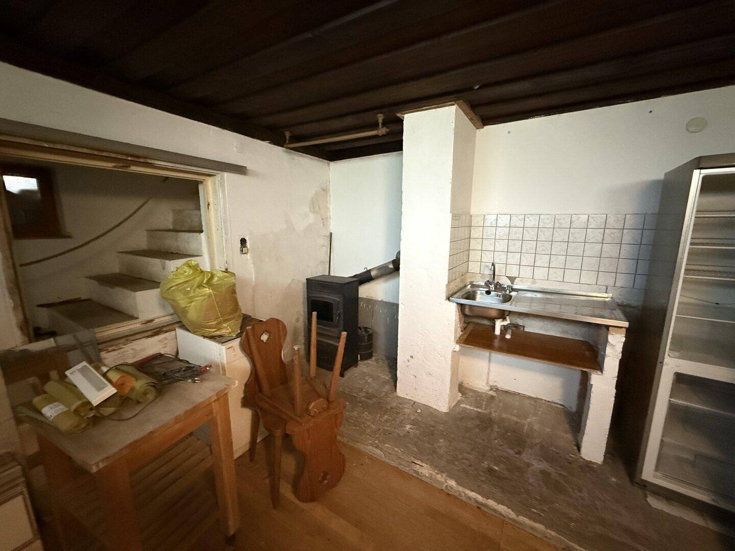 Rustikale Küchenzeile mit Spüle, Kühlschrank und einem Holzofen, mit Treppenzugang.