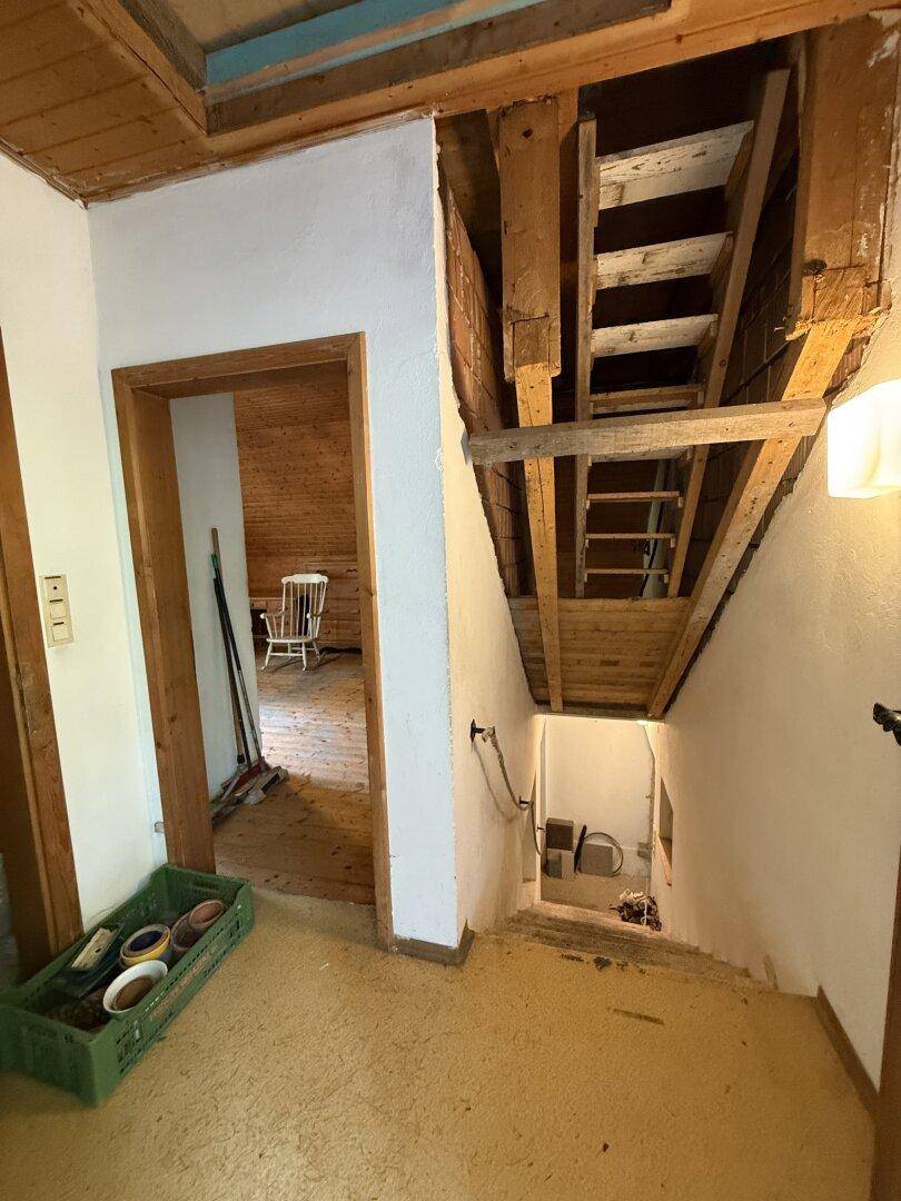 Flur mit offenem Treppenaufgang und sichtbaren Holzkonstruktionen, die das rustikale Ambiente betonen.