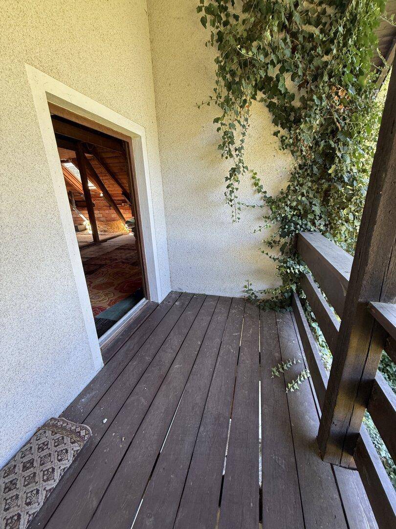 Kleiner Holzbalkon mit Kletterpflanzen, der einen Blick ins Grüne bietet.