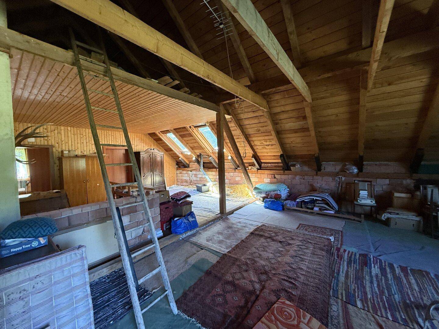 Heller Dachbodenbereich mit Holzverkleidung, Dachschrägen und mehreren Dachfenstern für Tageslicht.
