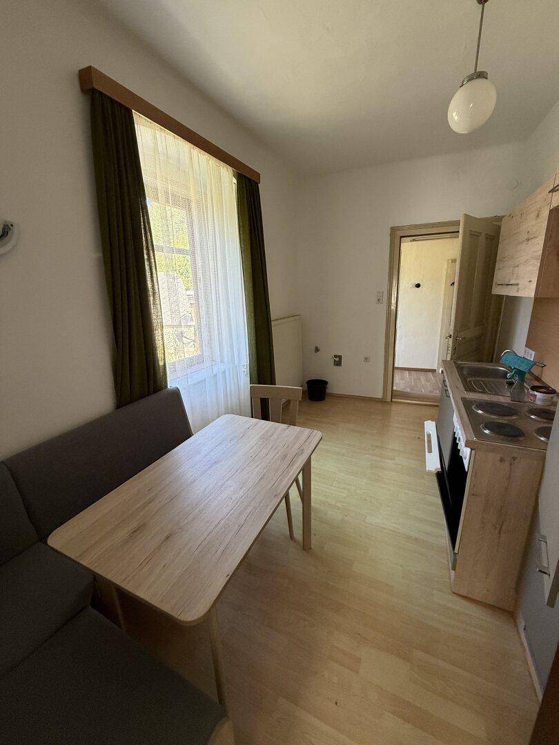 Kleine Küchenzeile mit Esstisch und Fenster, ideal für eine Einzelperson oder als Gästebereich.