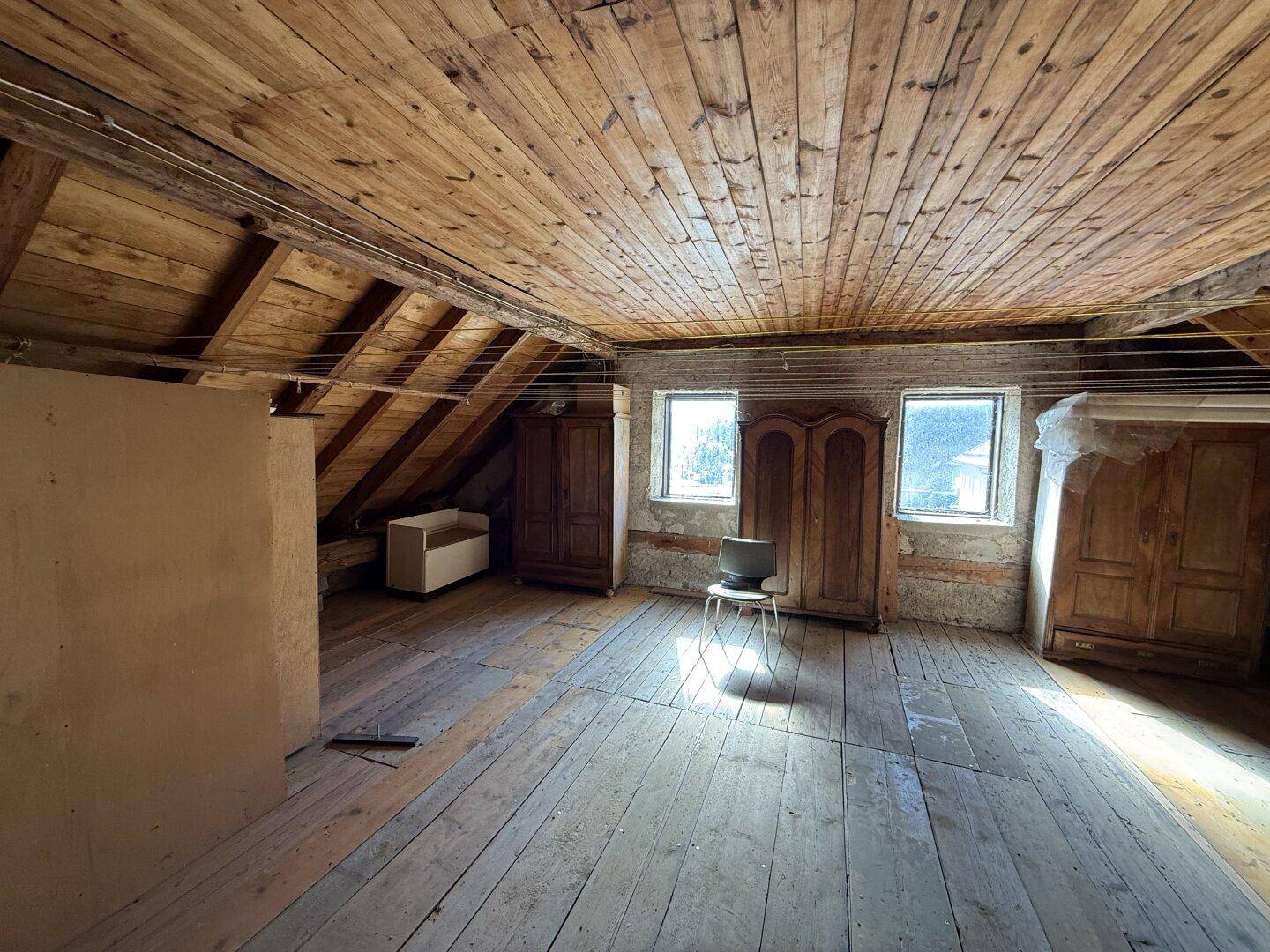 Geräumiger Dachboden mit Holzboden und sichtbaren Dachbalken, bereit für den Ausbau.