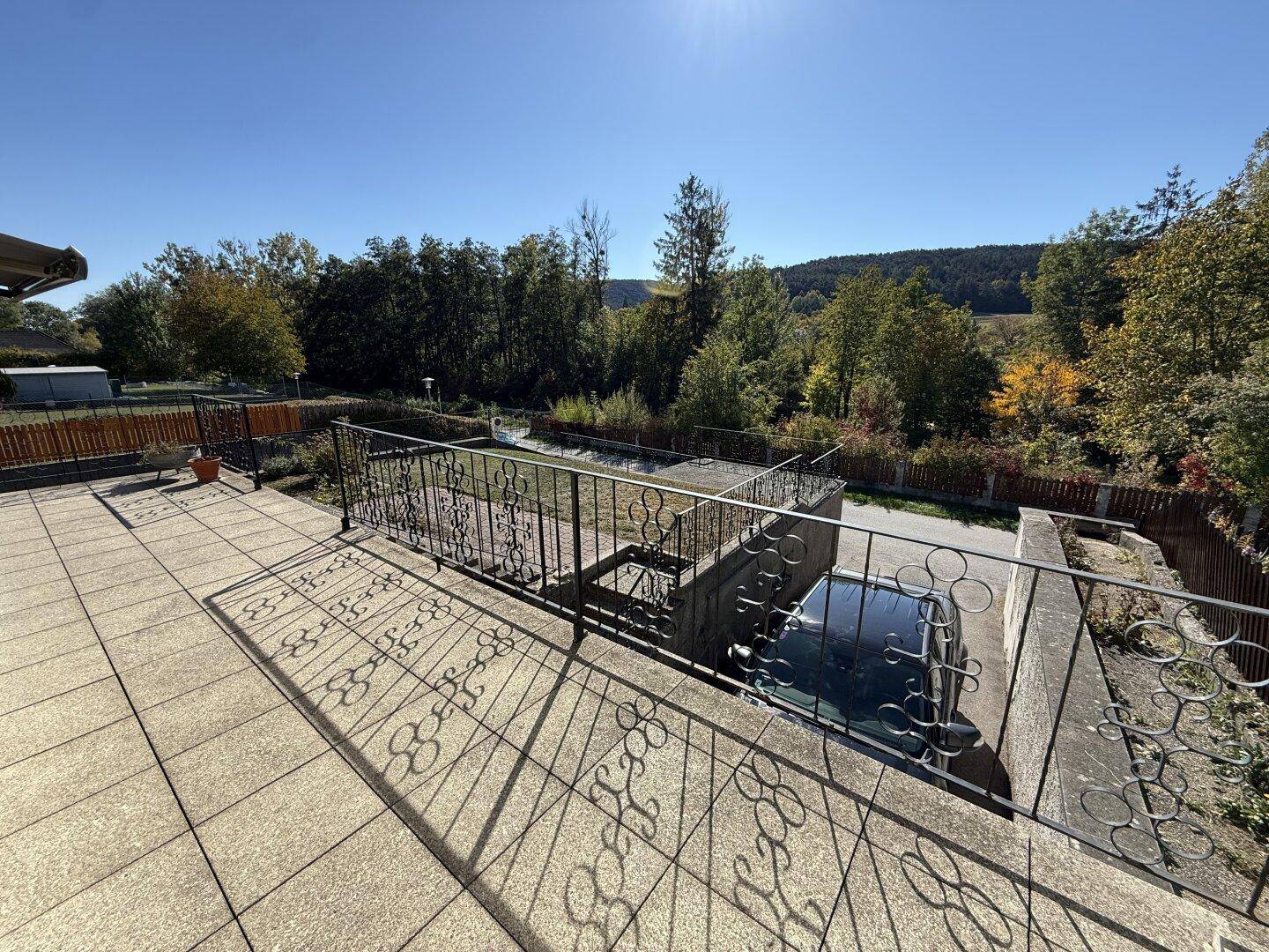 Große geflieste Terrasse mit schmiedeeisernem Geländer und weitem Blick ins Grüne.