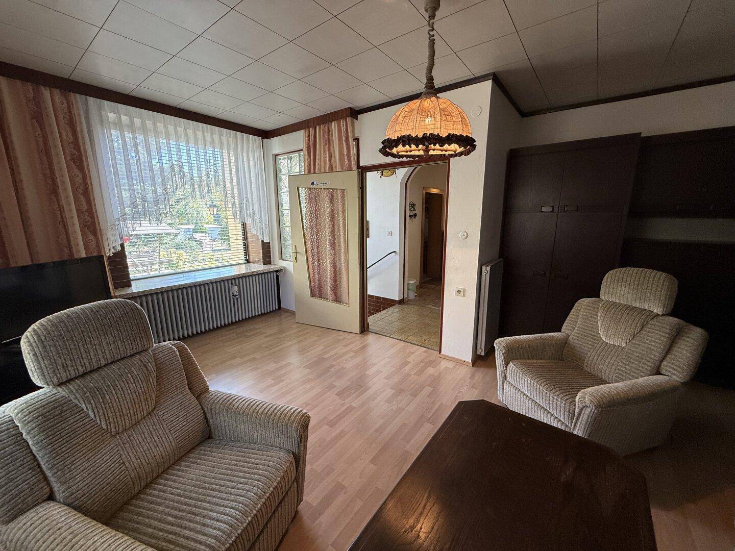 Geräumiges Wohnzimmer mit Laminatboden, beigen Möbeln und Zugang zum Flur.