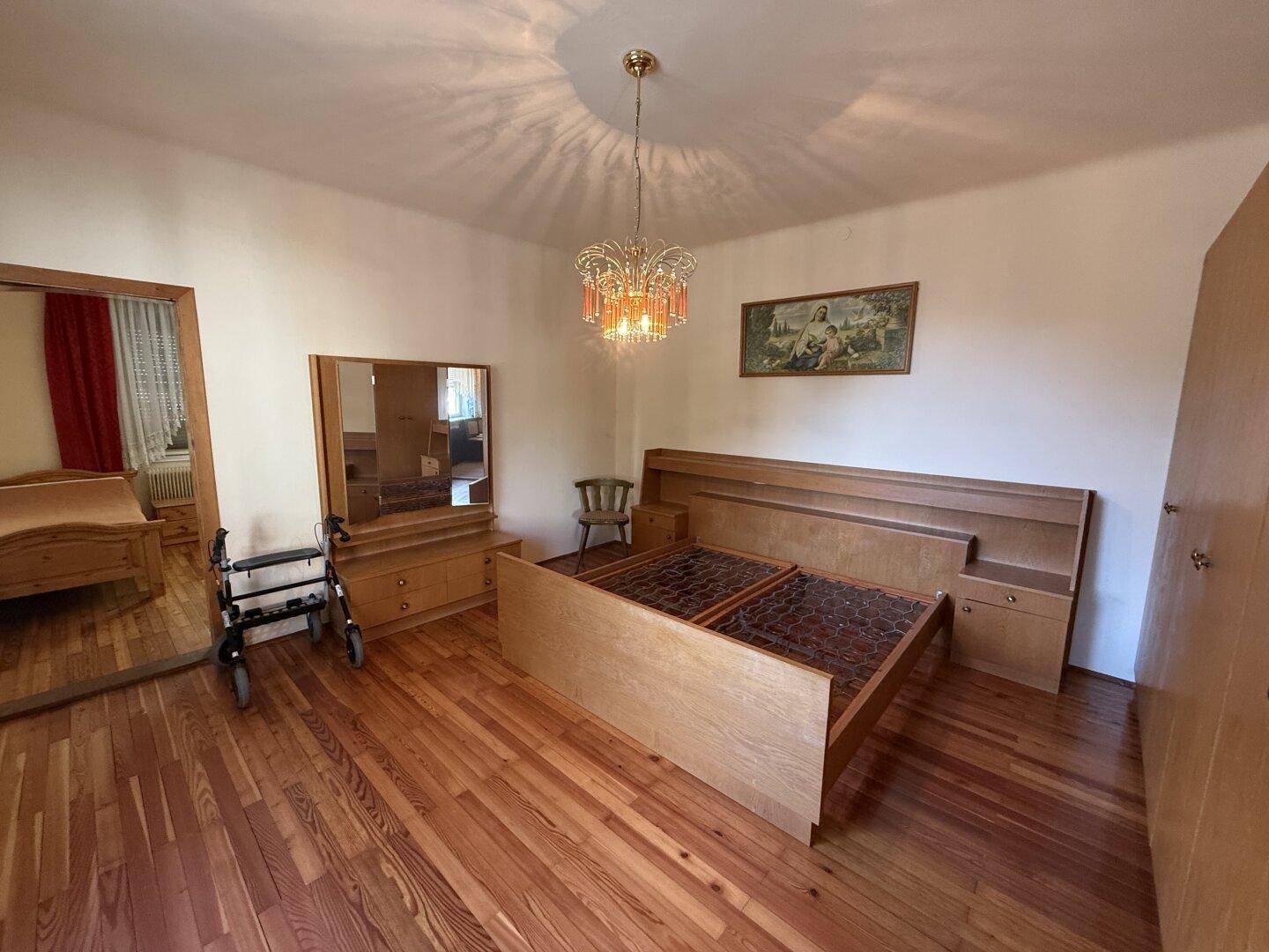 Schlafzimmer mit Holzboden, Doppelbett und Spiegelschrank im klassischen Stil.