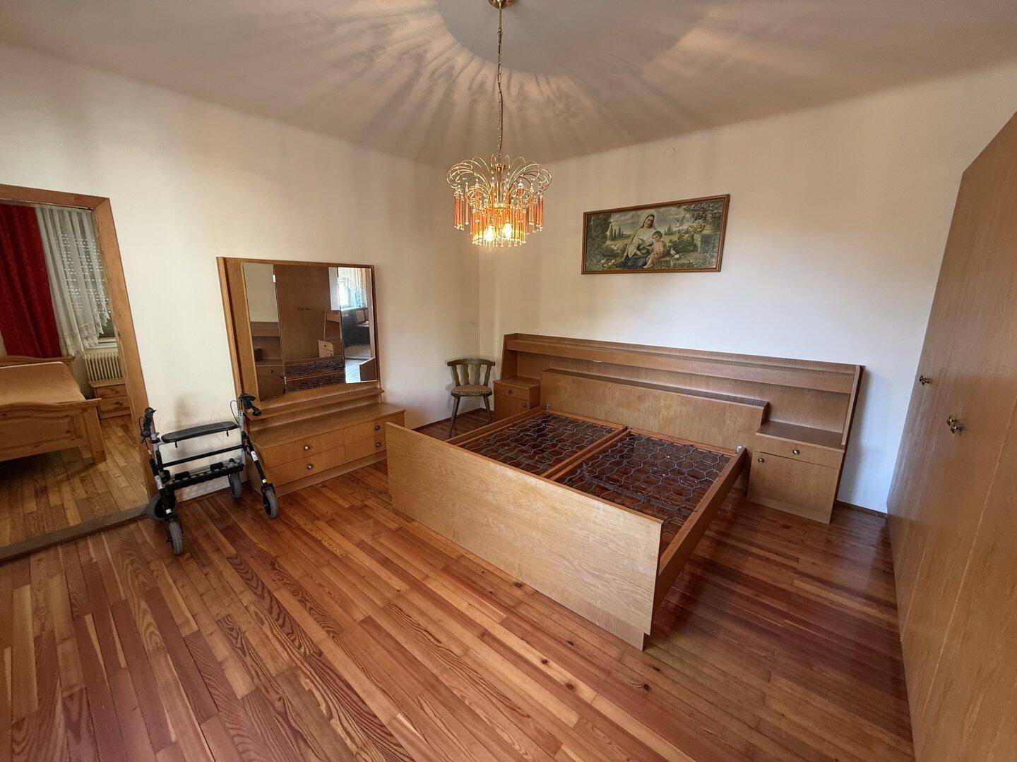 Geräumiges Schlafzimmer mit Holzboden, Doppelbett und Spiegelschrank.
