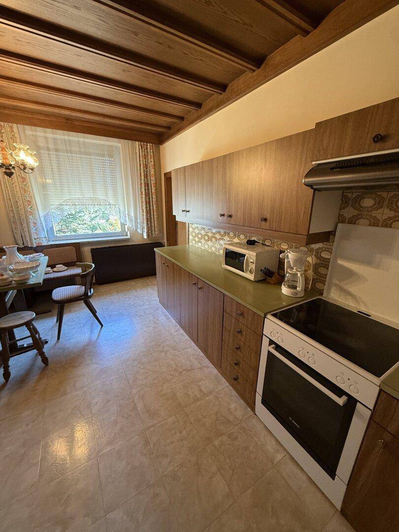 Traditionelle Küche mit Holzschränken, grünlicher Arbeitsplatte und integriertem Herd mit Backofen.