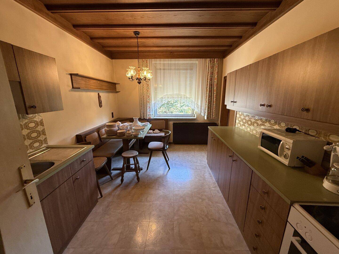 Geräumige Küche mit Essbereich, Holzdeckenbalken und funktionaler Ausstattung im traditionellen Stil.