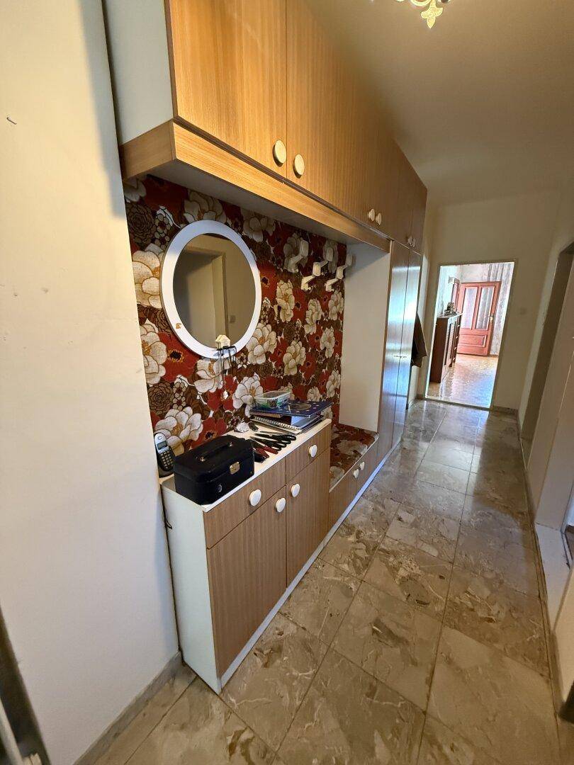 Schmaler Flur mit gemusterten Tapeten, Spiegelschrank und Fliesenboden.