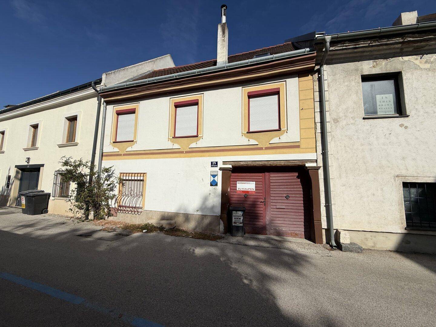 Vorderansicht eines charmanten Altbaus mit dekorativer Fassade und einem Verkaufsschild an der Tür.