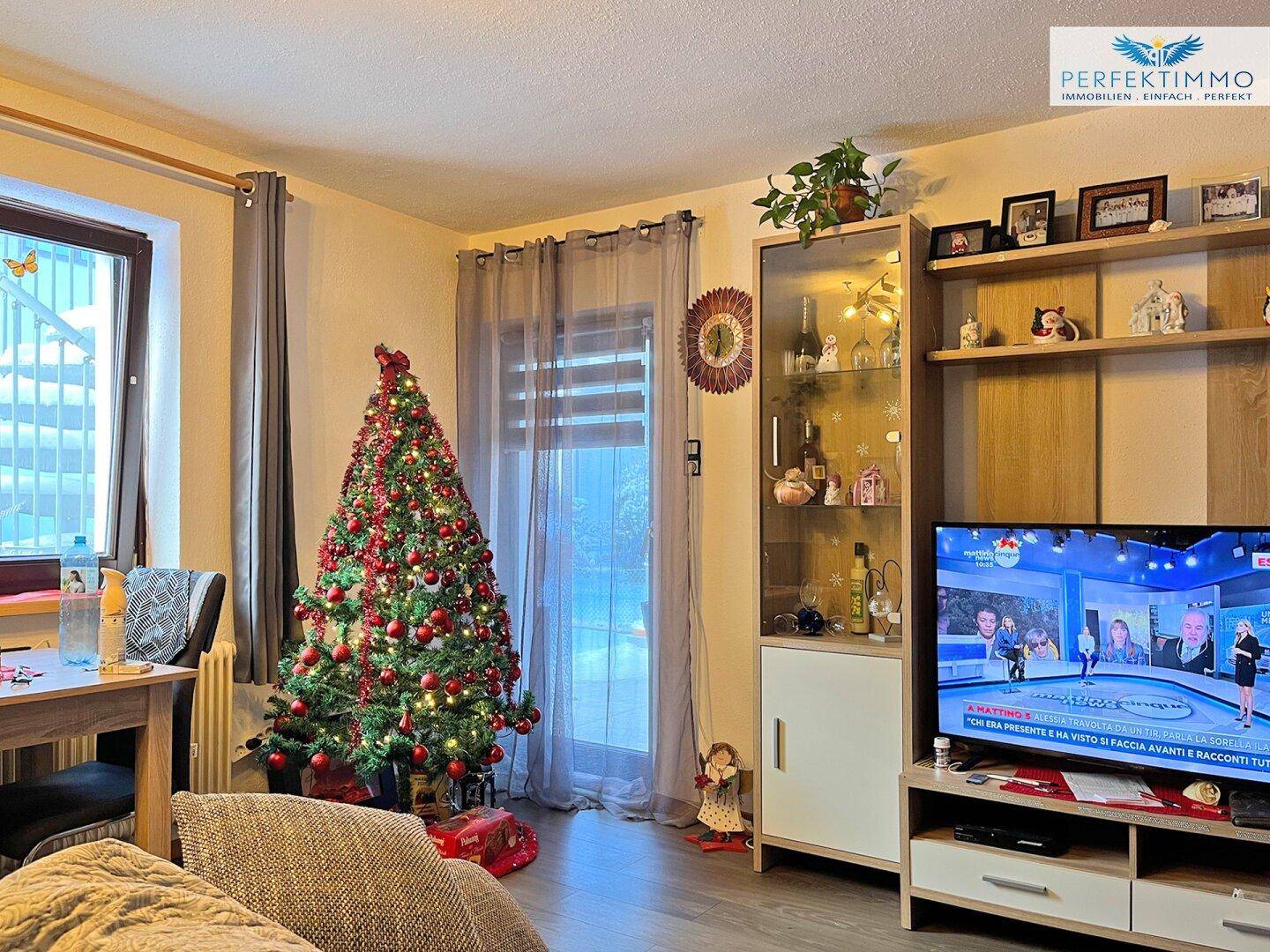 Gemütliches Wohnzimmer mit Weihnachtsbaum, TV-Möbel und dekorativen Elementen.