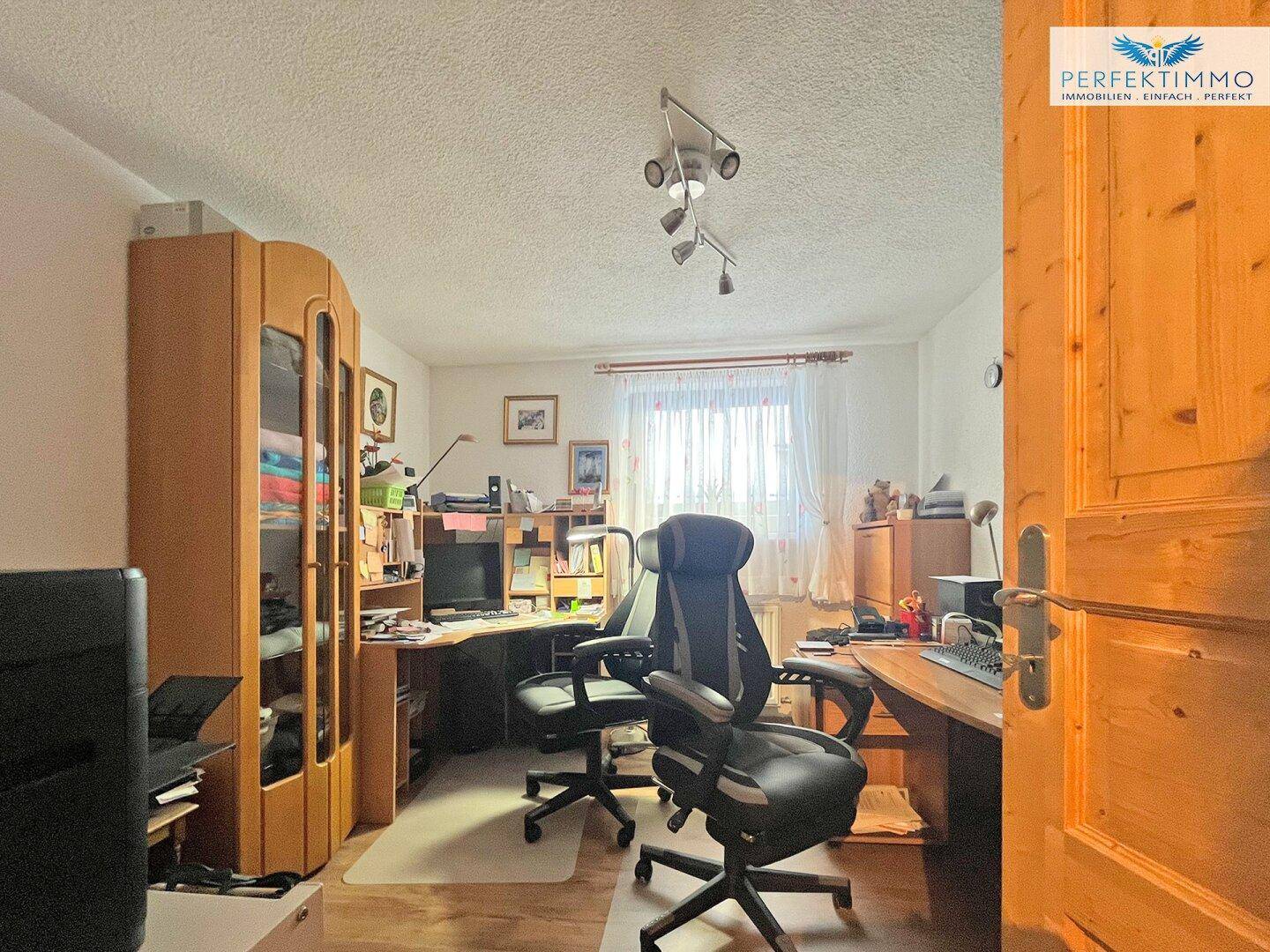Funktionales Büro mit Schreibtisch, Bürostühlen und Holzmöbeln.