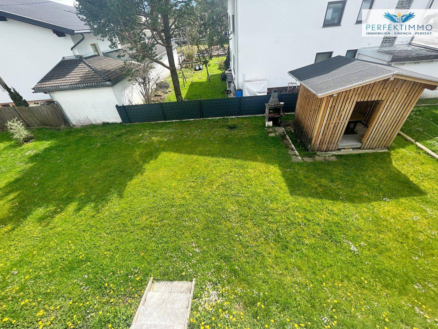 Großer, sonniger Garten mit Rasenfläche, Gartenhaus und Kinderrutsche.