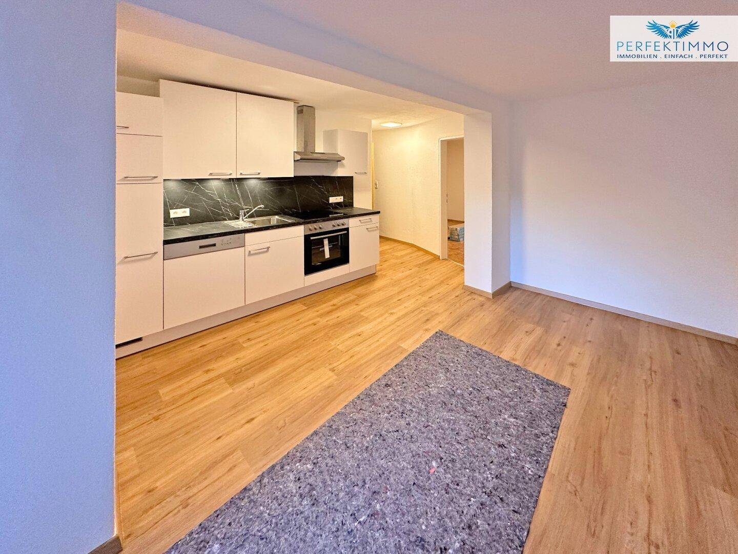 Offene Küche mit Laminatboden und Blick in den angrenzenden Wohnbereich.