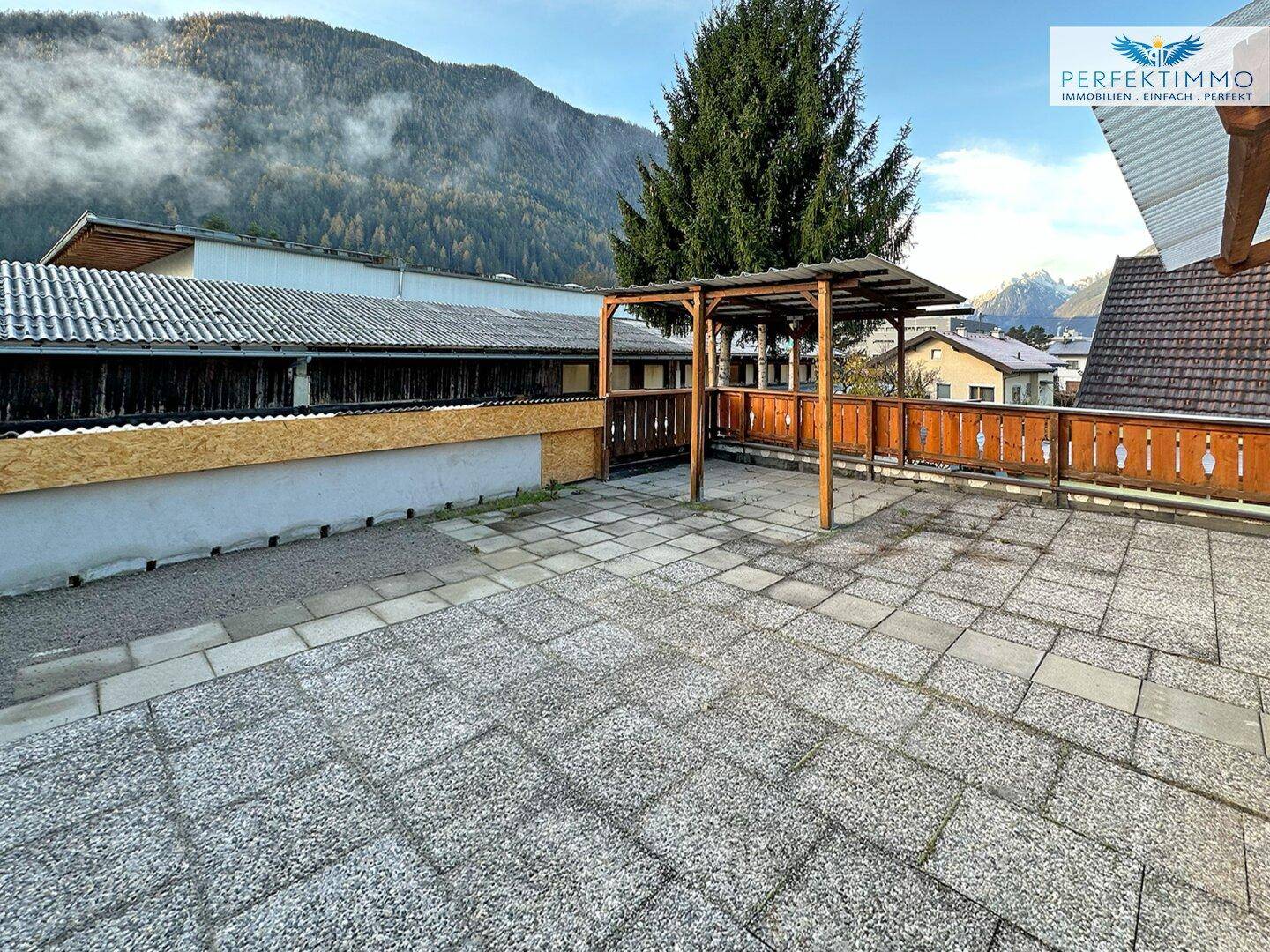 Große gepflasterte Terrasse mit Pergola und Bergblick, ideal für Entspannung.