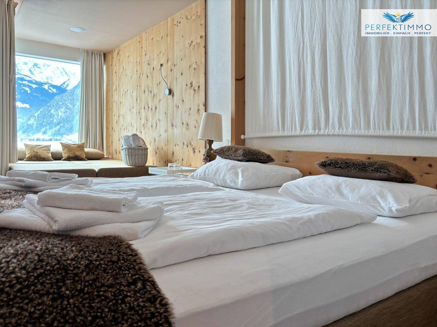 Schlafzimmer mit Holzwänden und einem großen Fenster, das einen malerischen Bergblick bietet.