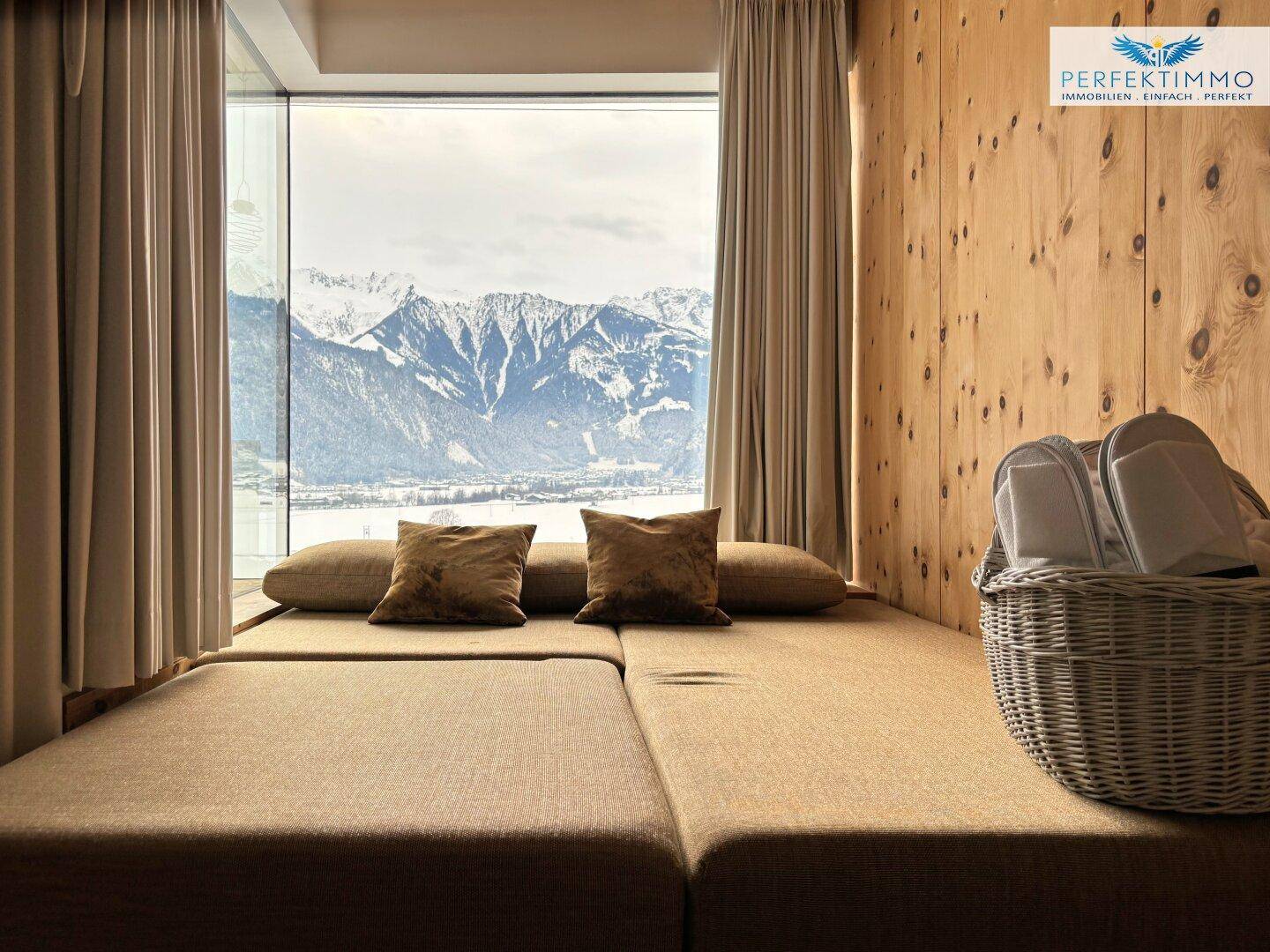 Entspannungsbereich mit bequemen Liegen und einer beeindruckenden Fensterfront mit Bergblick.