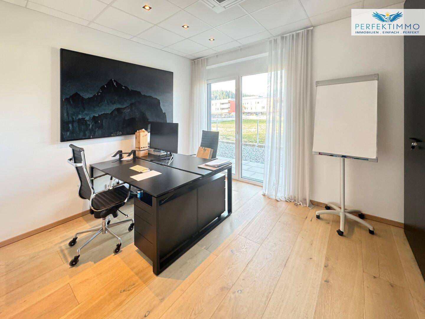 Modernes Büro mit Holzboden, großem Schreibtisch und direktem Zugang zu einem Außenbereich durch eine Glastür.