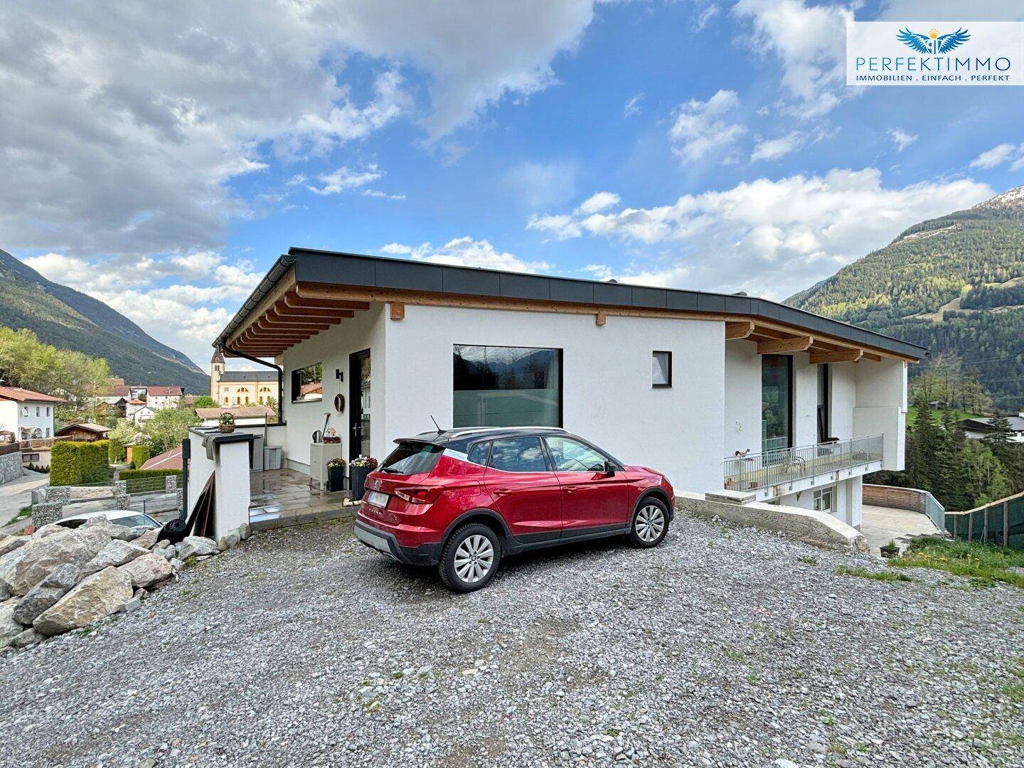 Seitenansicht des modernen Hauses mit Stellplatz und weitem Blick auf die umliegende Natur.