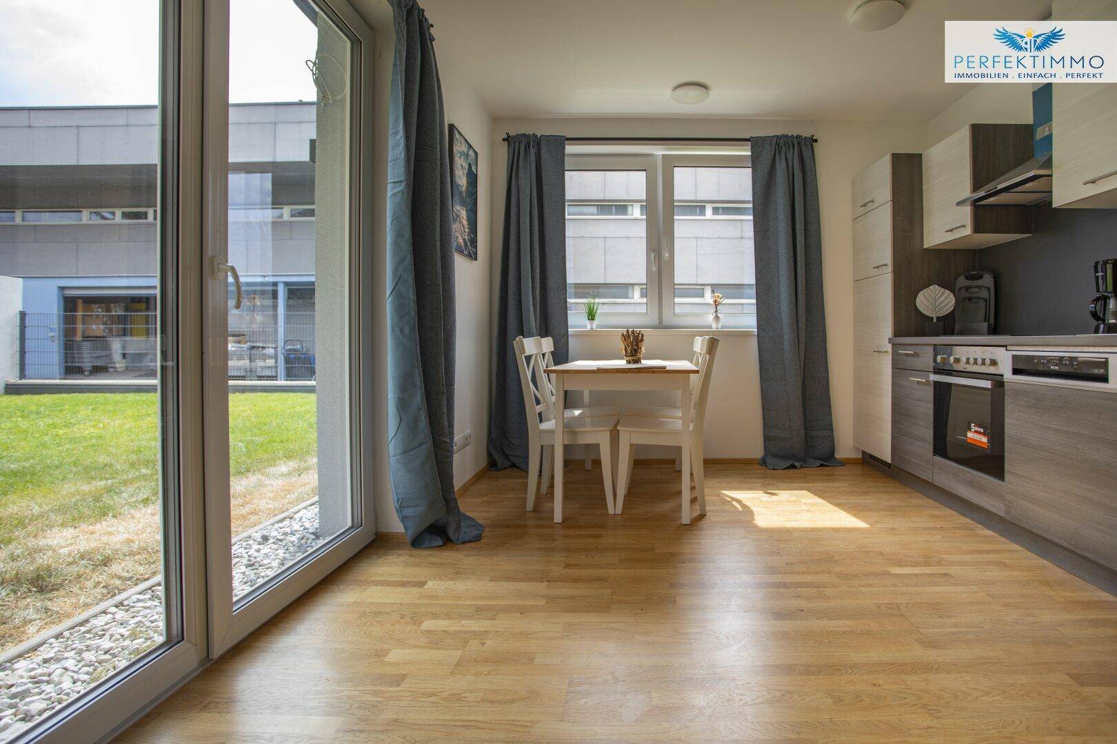 Moderne Küchenzeile mit Essbereich und großen Fenstern zum Außenbereich.